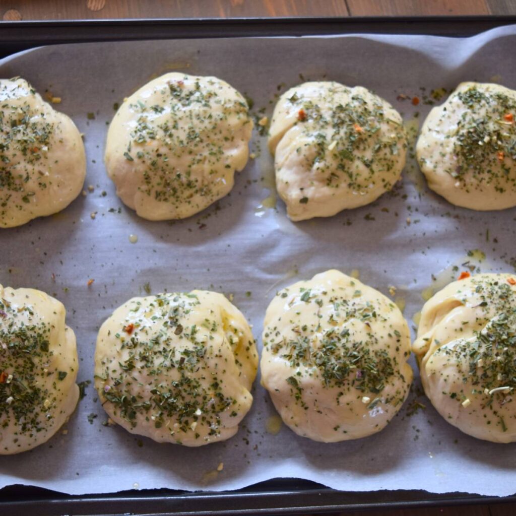 Super Simple Cheesy buns small dough balls seasoned before cheese on parchment paper. 