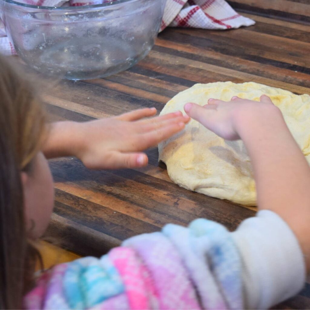 Super Simple Homemade White Bread pushing out air bubbles before folding into pan